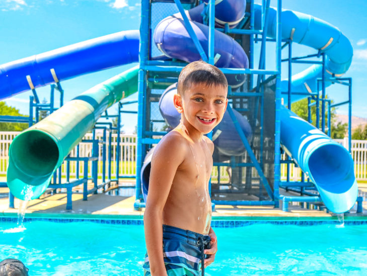 A camper standing in front of the water slides by the pool.
