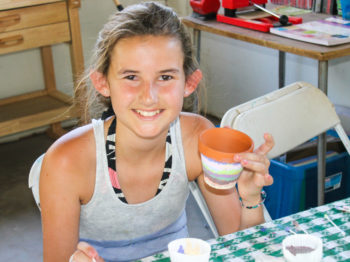 A camper painting a ceramic pot.