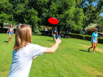 A camper throwing a frisbee during a game of frisbee golf.