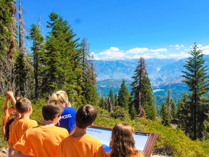 Campers looking over a mountain range in the distance while on a hike.