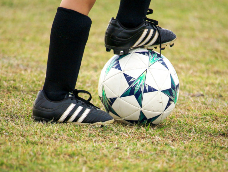 A camper with their foot on a soccer ball about to kick.