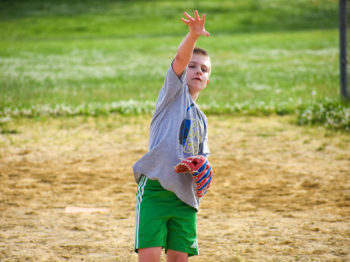 A camper throwing a ball while playing softball.