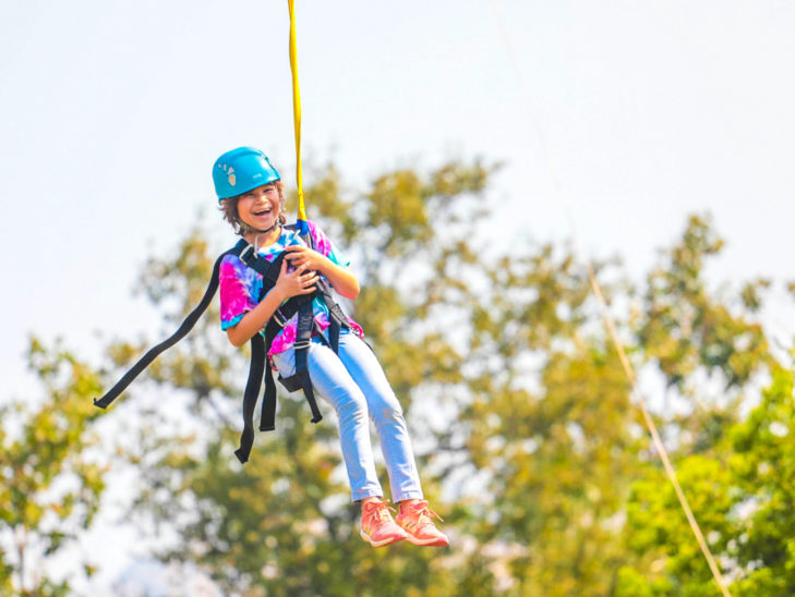 A camper laughing while going down a zip line.