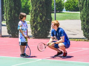 A camper learning how to play tennis