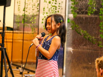 A camper standing with a microphone practicing her vocals.