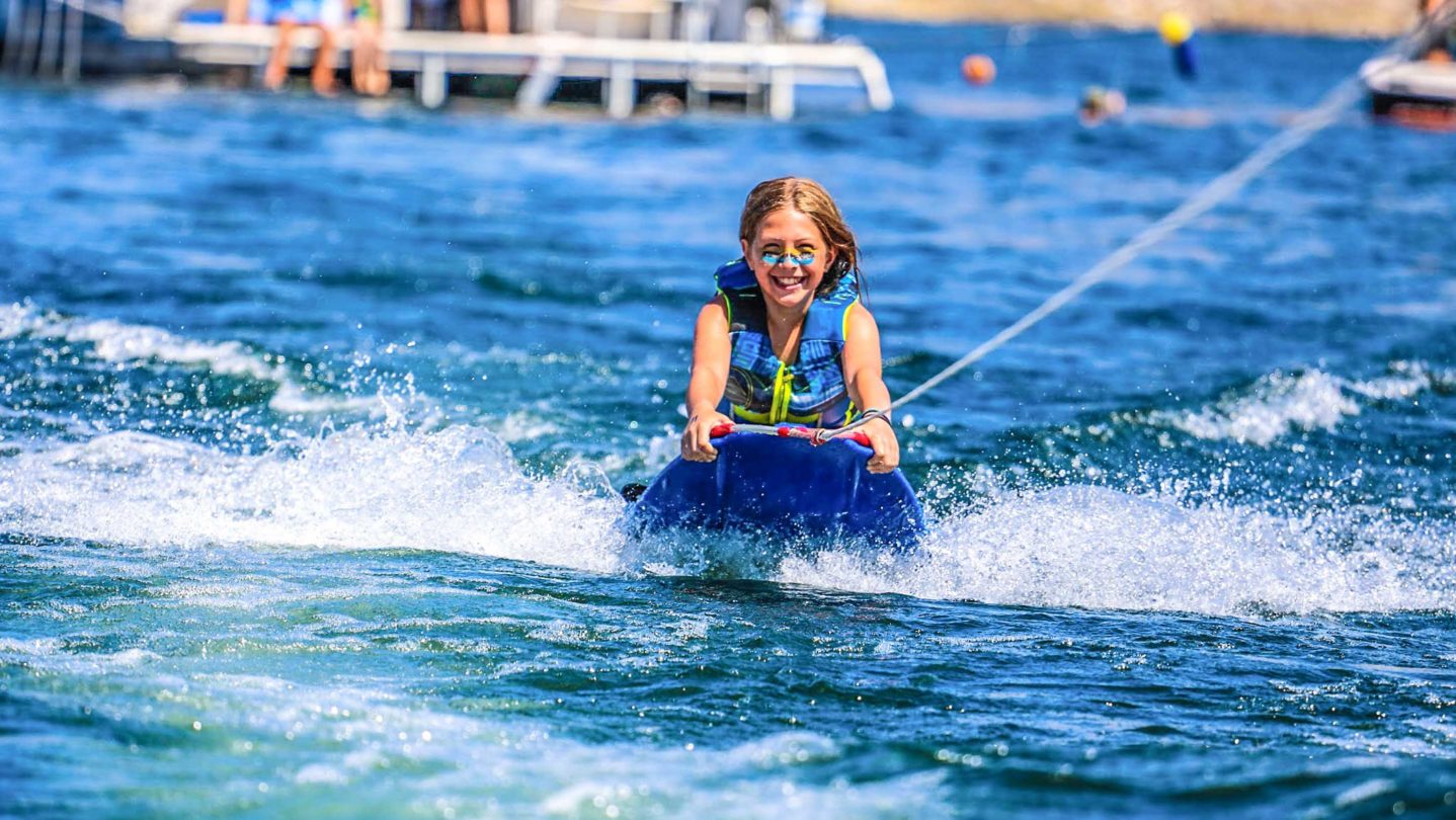 A camper wakeboarding and smiling