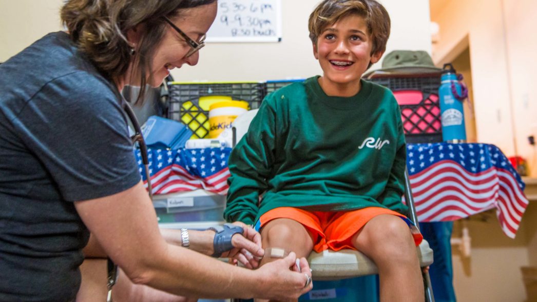 A camper getting a bandaid put on his knee.