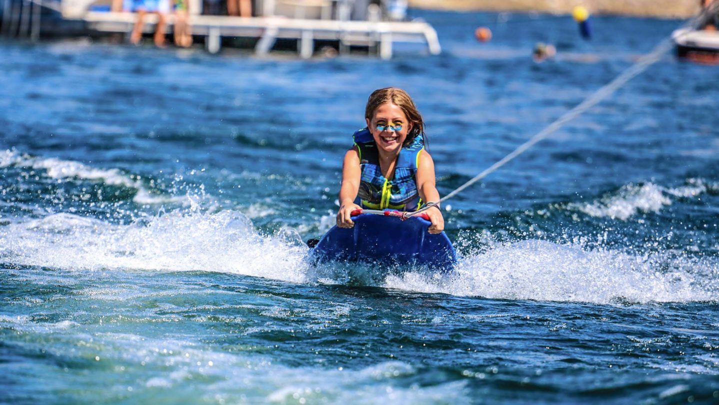 A camper smiling on a wakeboard
